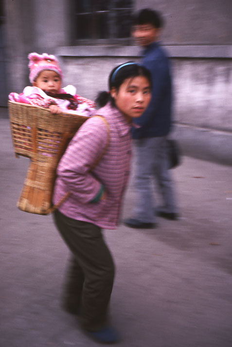 Mother carrying her child in a basket on her back