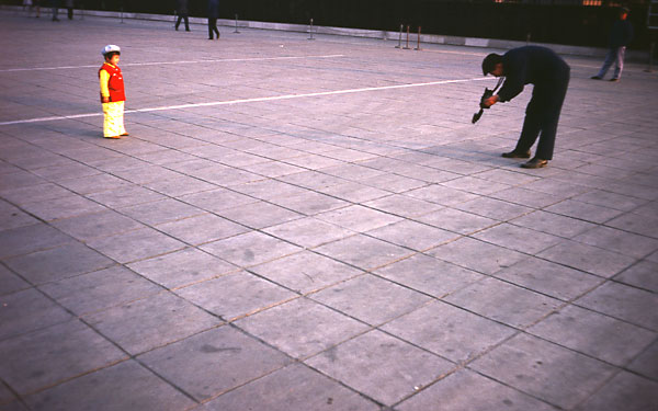 father photographing his daughter on beijing tian an men square sunset