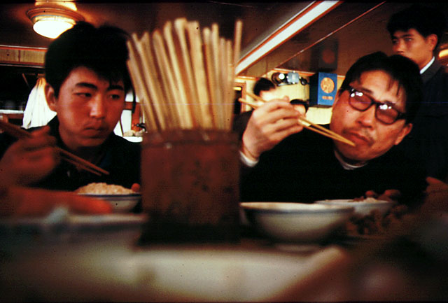 Boy and man eating with chopsticks, a chopstick holder