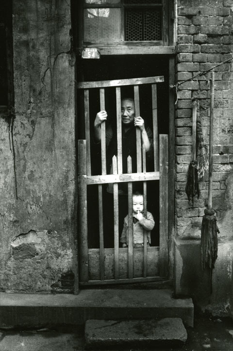 woman and child peeking through home gate Shangai