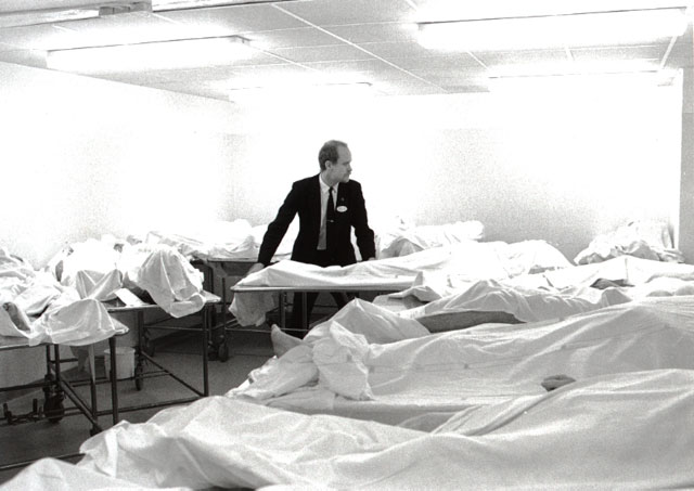 Undertaker in the morgue among tens of dead bodies