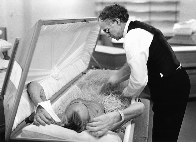 Undertaker shrouding a dead man