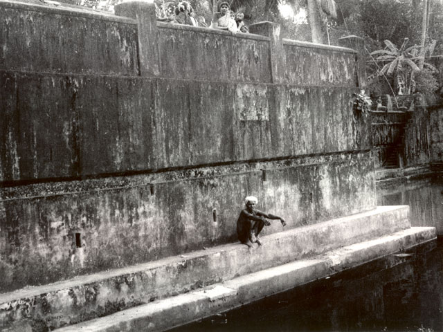 Man sitting squatting by Kutithirta the holy pool in Gokarna