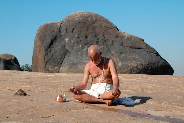 hampi pilgrim performing puja with holy shit and holy urin and huge boulder