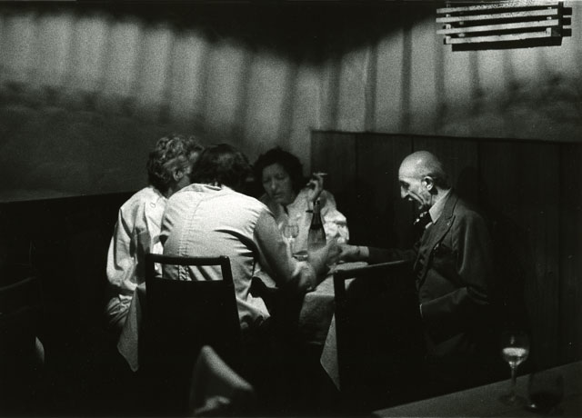 three women and one man sitting at table pague
