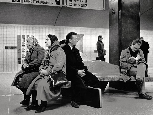 Stockholm subway, two muslim women, two swedish men with traditional looks sitting on a stone bench waiting for the subway to arrive