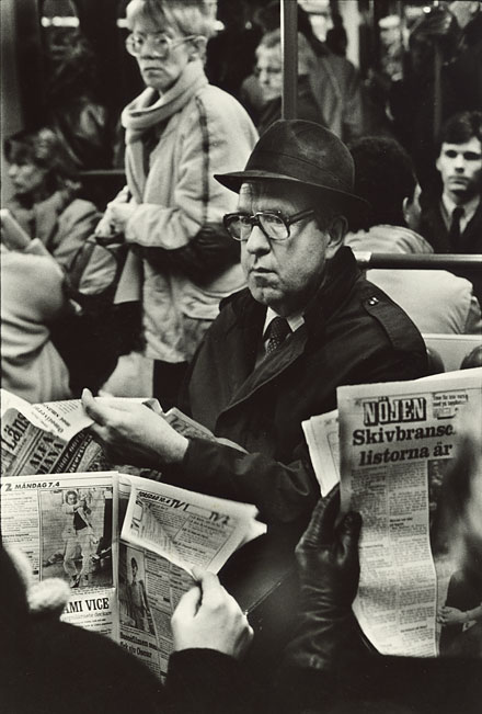 Stockholm subway, man with big glasses and an old fashioned hat reading news paper