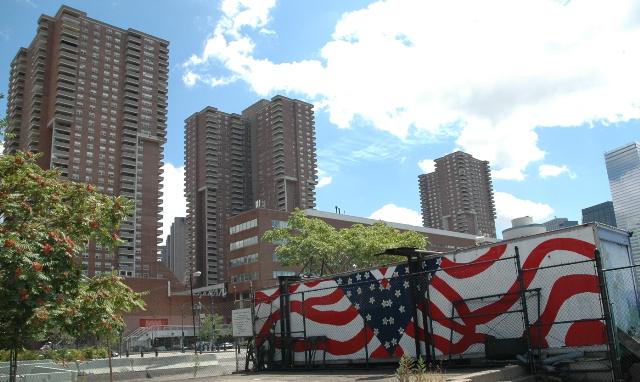 american flag by West Side Highway with sky skrapers in the background