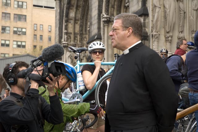 The Rev. Canon Thomas Miller is interviewed by a film team. Female bike rider in the background. Blessing of the Bikes at The Cathedral Church of St. John the Divine