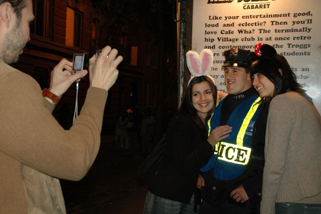 Halloween, police posing with two girls with bunny ears, man photographing them with two cameras simultaneously at Cafe Wha