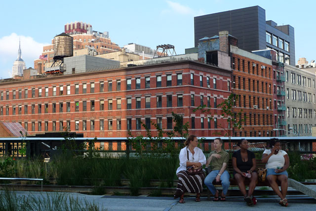 People sitting on a bench on High Line, Empire State Building in the background