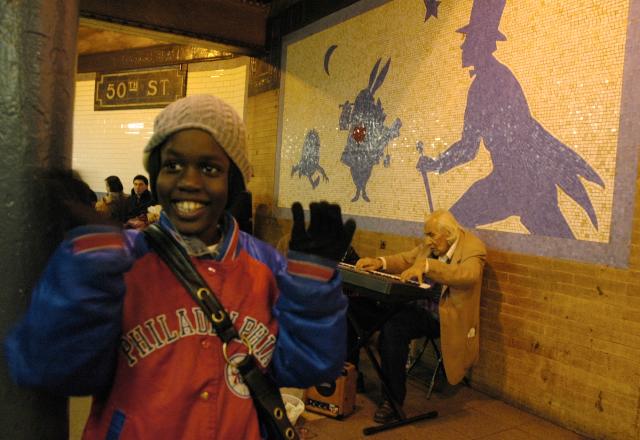 A happy kid at 50th Street subway stop, musician in the background. Murals Alice in Wonderland, New York