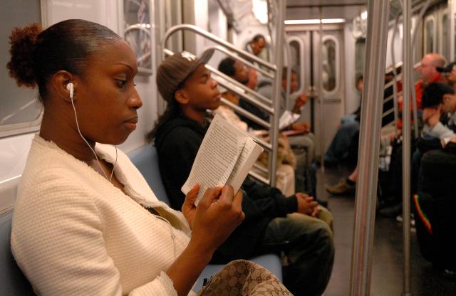 Woman reading in New York subway with iPod