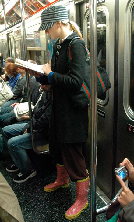 Woman reading book in New York subway MTA. Red boots with yellow dots